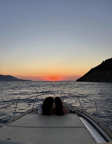 A sunset over the ocean with two people on a boat. 1