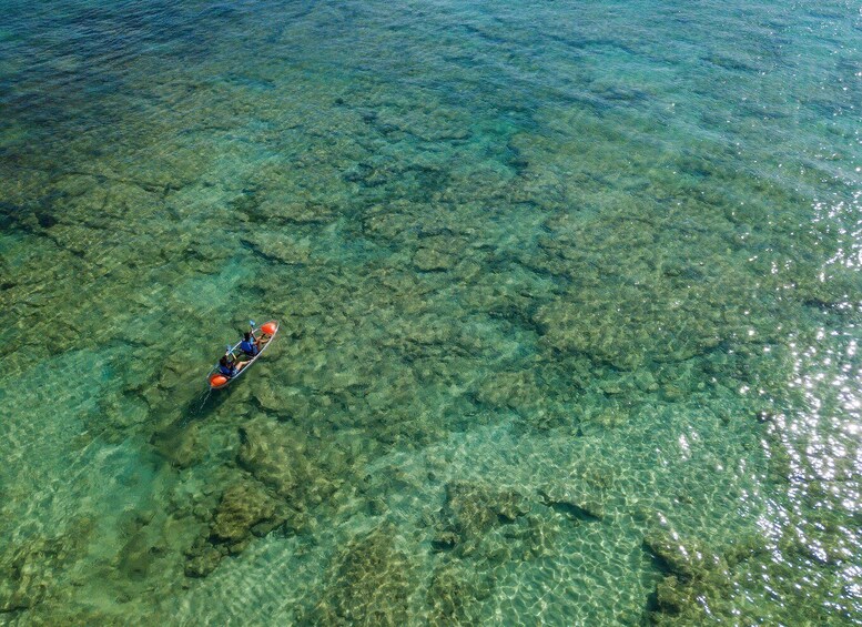 A person kayaking on clear, shallow water. 3