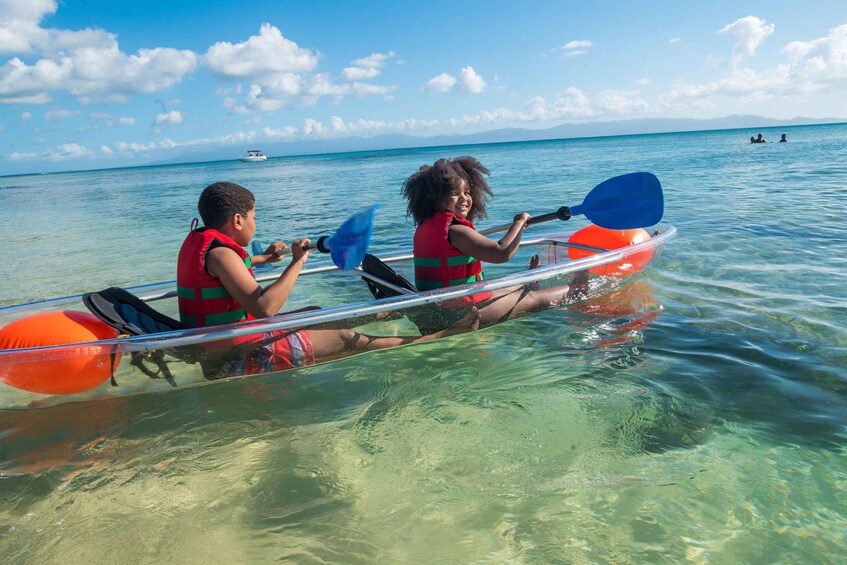 Two people kayaking on a clear blue sea with a boat in the distance. 4
