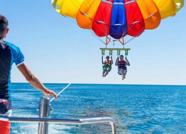 A person parasailing over the ocean with a colorful parachute. 3