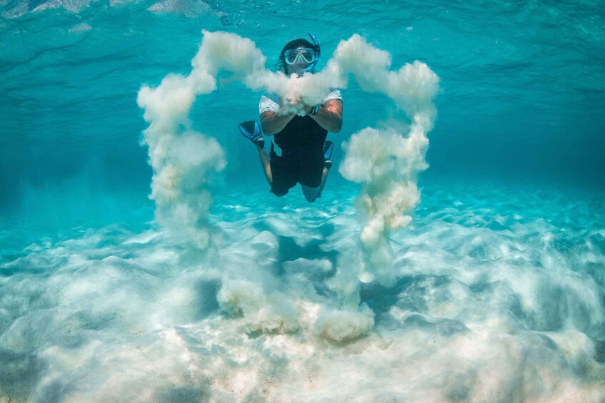 A diver surrounded by a cloud of bubbles in clear blue water. 2