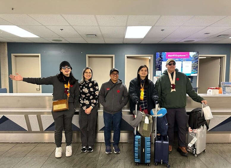 A group of people standing in an airport terminal with luggage. 3