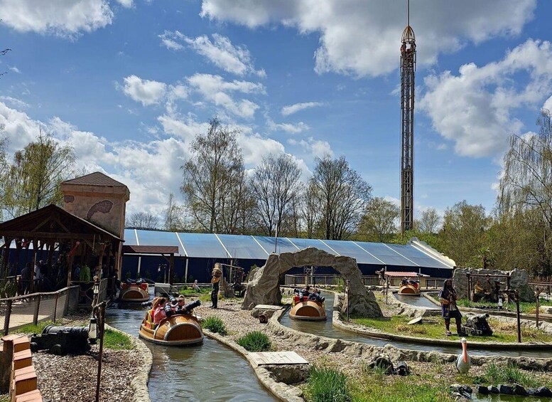 A water ride with boats, a tall tower, and a building with solar panels. 4