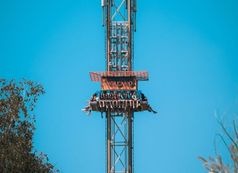 A ride with the name 'VOLCANO' on a tall structure against a clear blue sky. 1