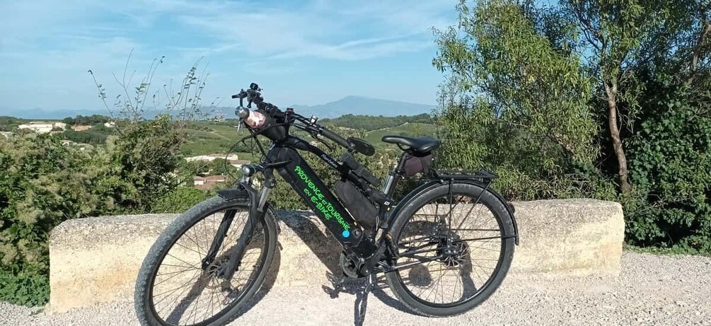 A black electric bike parked on a concrete ledge with a scenic view of hills and trees in the background. 2