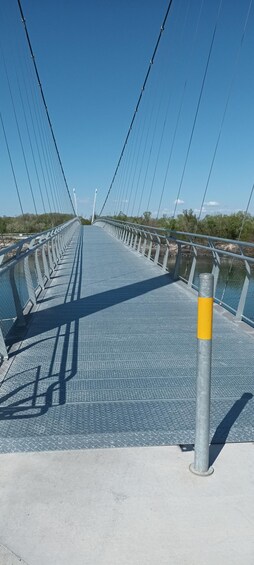 A pedestrian bridge with metal railings and a textured walkway. 4