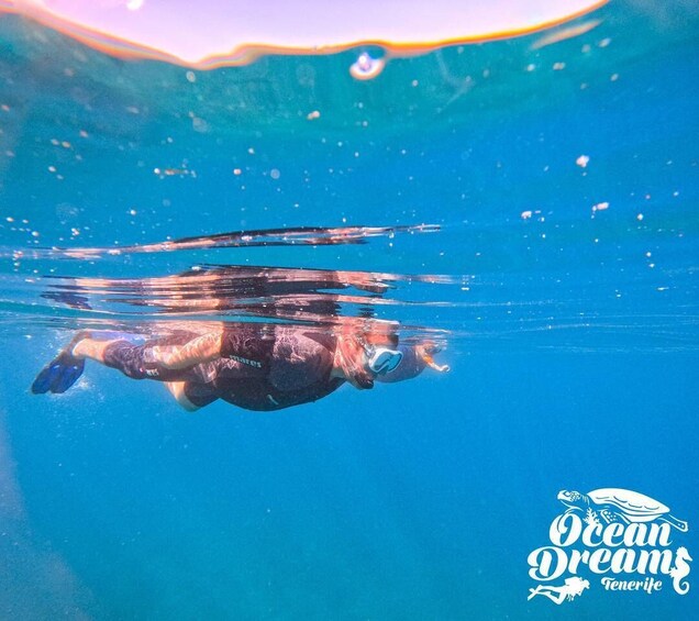 A person swimming underwater with bubbles, surrounded by clear blue water. 3