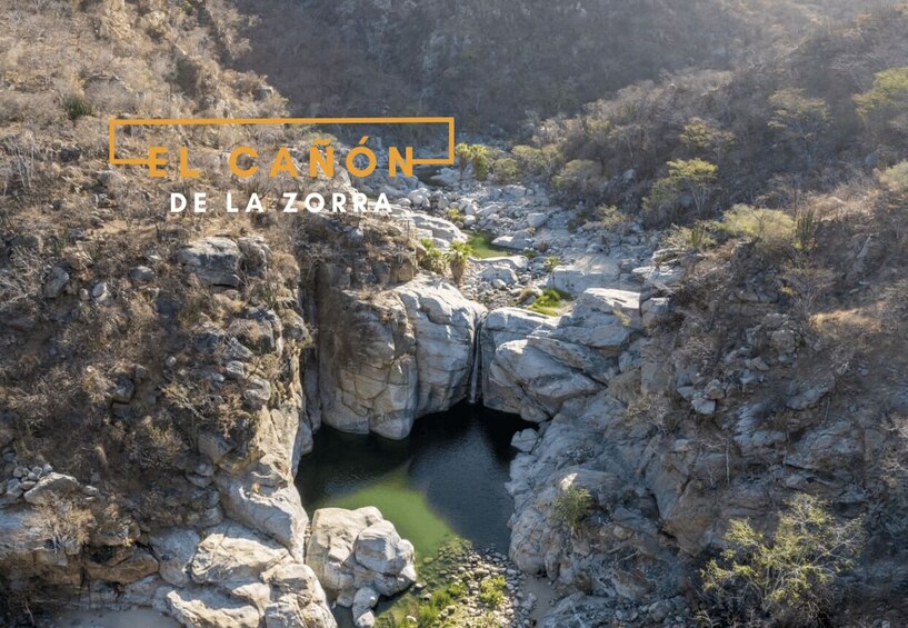 A canyon with a narrow water passage surrounded by rocky terrain and sparse vegetation. 4