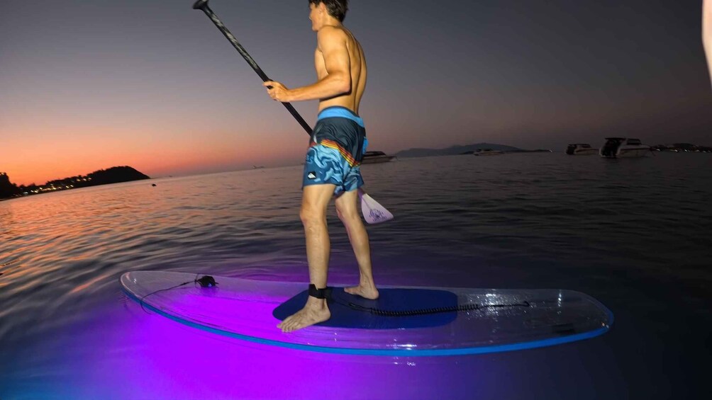 A person paddleboarding on a body of water at sunset. 5