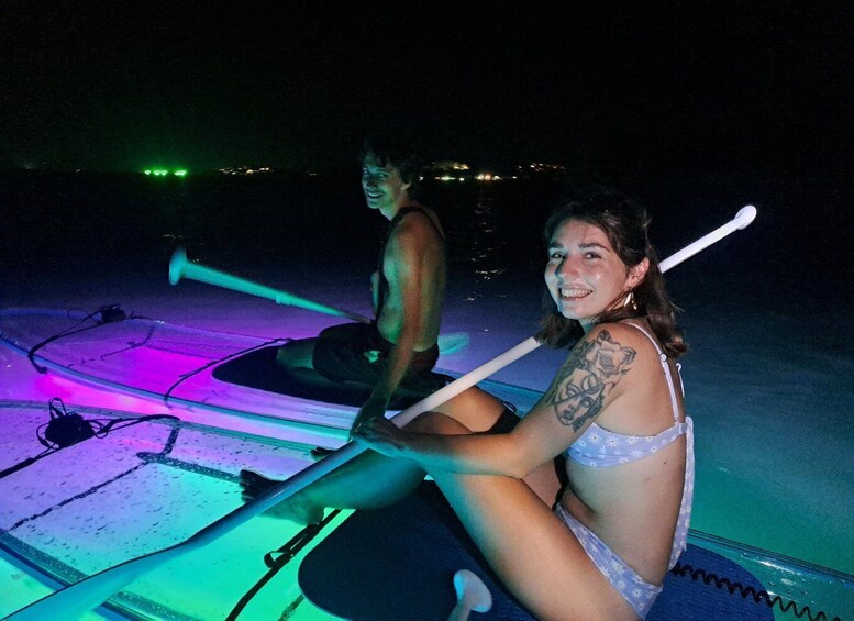 A person rowing a boat at night with colorful lights. 5