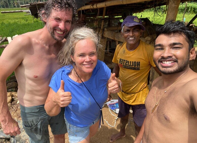 Four people outdoors, one giving a thumbs-up, with a rural background including a bamboo structure and greenery. 4