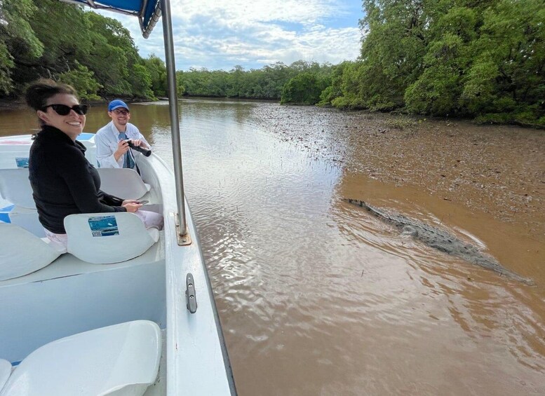 A boat on a muddy river with a crocodile swimming nearby. 1