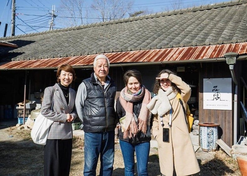 A group of people standing in front of a traditional Japanese building with a tiled roof. 3