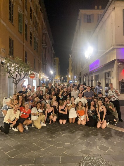 A group of people posing for a photo on a city street at night. 4