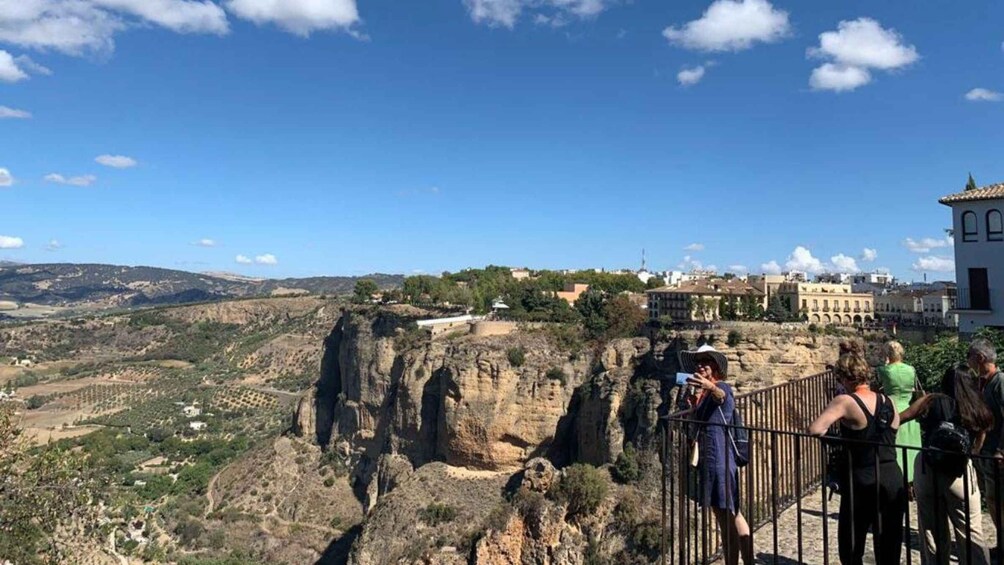A rocky cliff overlooking a valley with buildings in the distance. 5
