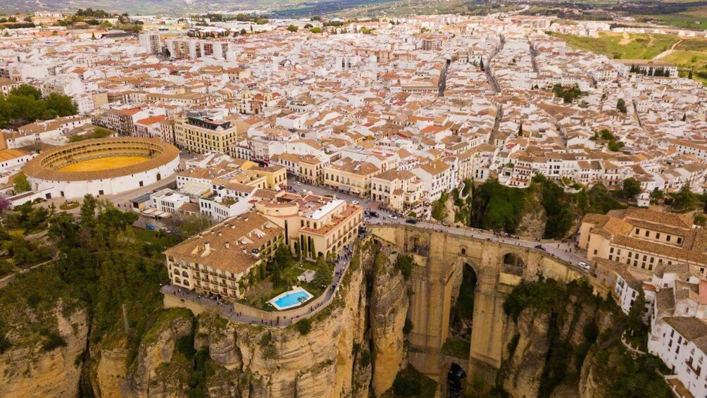 A coastal city with a prominent cliffside structure, a large stadium, and a historic bridge. 3