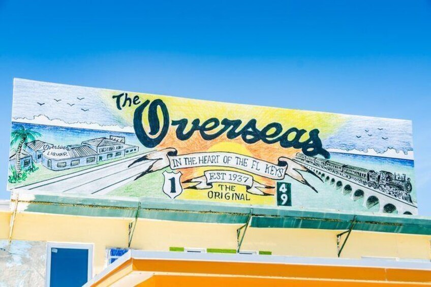 A mural with the text 'The Overseas' and 'In the Heart of the FL Keys' on a building. 1