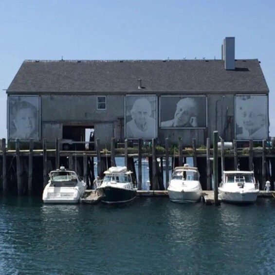 A building with multiple portraits on its facade, docked boats, and a clear blue sky. 4
