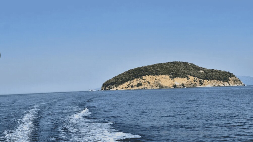 A small island with a rocky coastline and a clear blue sky. 5