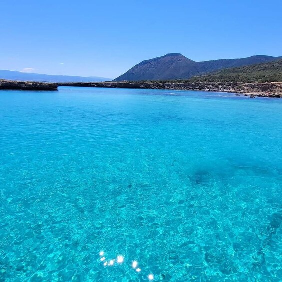 A clear blue sea with a mountain in the background. 1