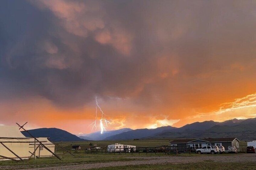 A rural landscape with mountains, a farmhouse, and a lightning strike in the sky. 4
