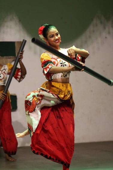 A person performing a dance with a colorful skirt and a black staff. 5