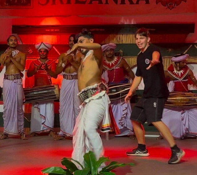 A group performing a traditional dance with cultural attire and a red backdrop. 3