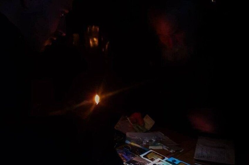 A dimly lit room with a lit candle, scattered papers, and a small table. 3