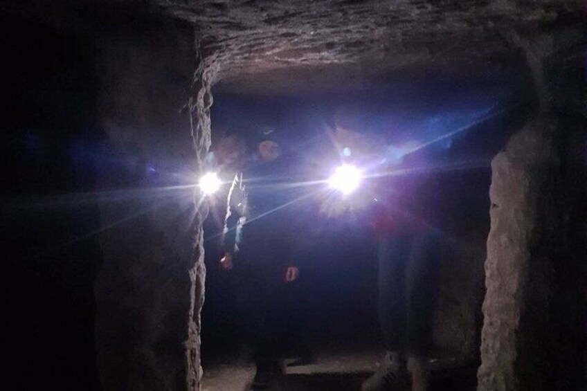 A cave with rough rock walls and a person holding a light source. 5