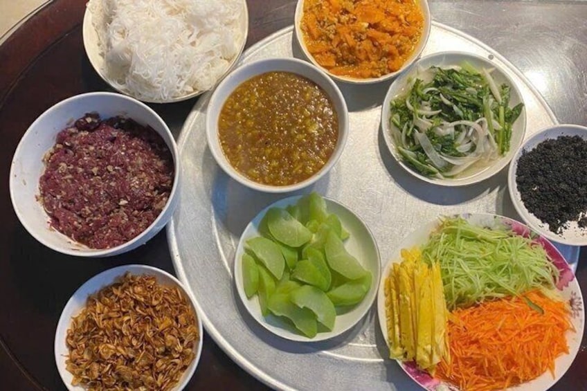 A tray with various food items including noodles, meat, vegetables, and sauces. 5