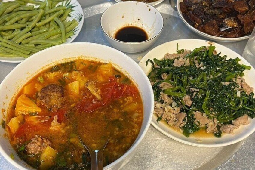 A meal with a bowl of soup, a plate of greens, and a bowl of beans. 3