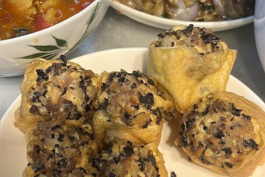 A plate of stuffed pastries with visible fillings and a bowl of soup in the background. 2