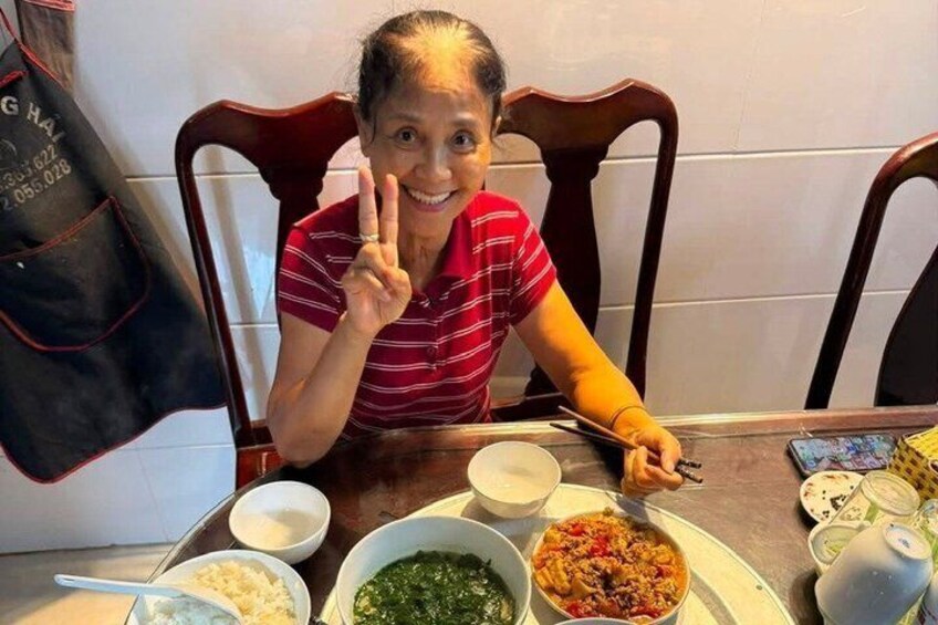 A person sitting at a table with various dishes, including rice, greens, and a pasta dish. 4