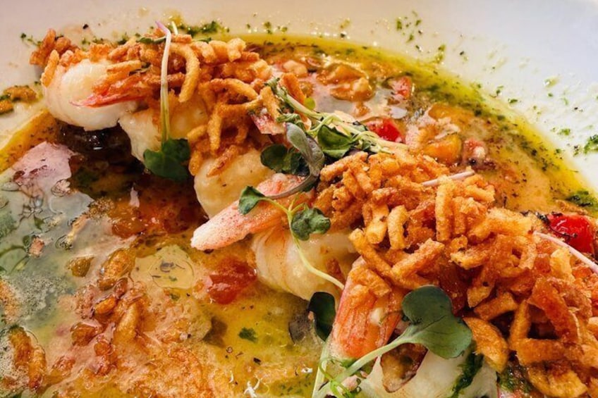 A seafood dish with shrimp, greens, and crispy garnish. 4