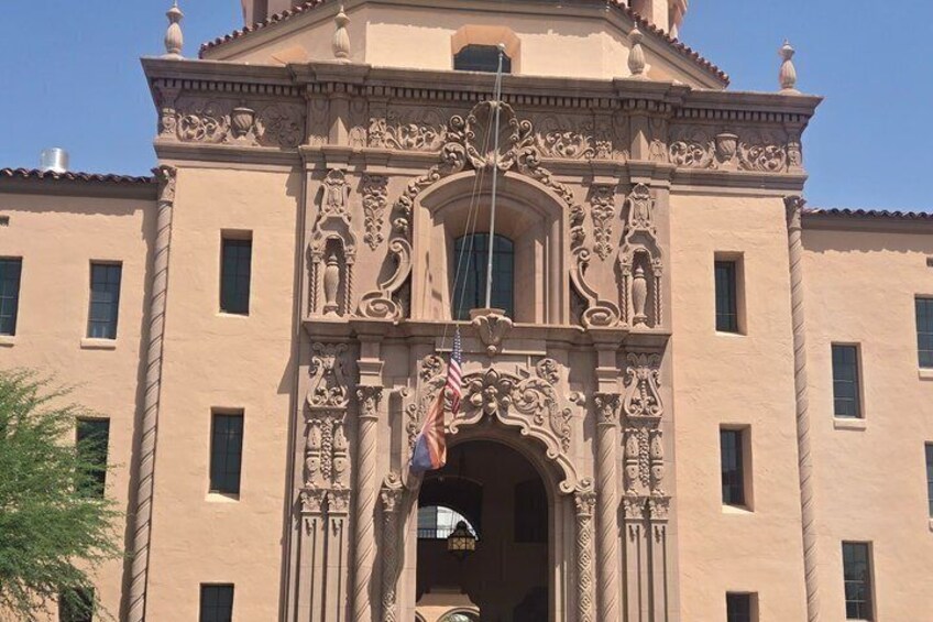 A building with ornate architectural details, a large arched entrance, and flags. 3