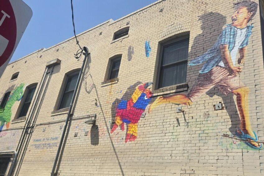 A brick building with a colorful mural of a person playing a guitar. 2