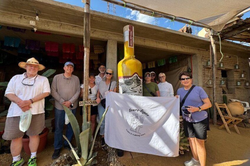 A group of people standing in front of a building with a large bottle and a flag. 3