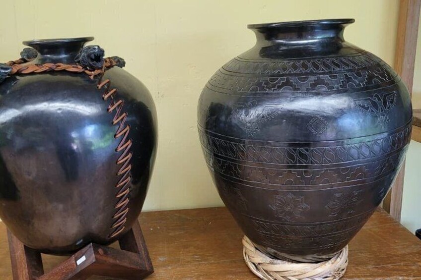 Two dark-colored ceramic vases with intricate patterns and designs on a wooden surface. 5