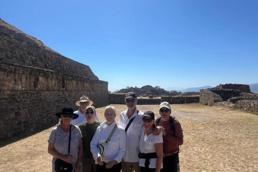 A group of people standing in front of ancient ruins with stone walls and a clear sky. 4