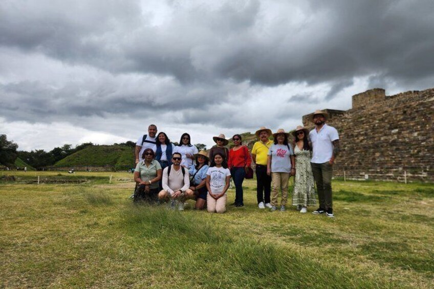 A group of people posing in front of a historical stone structure. 1