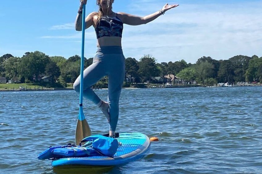 A person paddleboarding on a calm lake with trees and houses in the background. 3