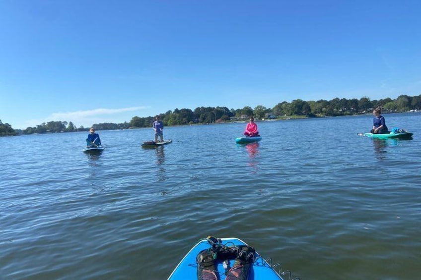People paddling kayaks on a calm lake with trees in the background. 5