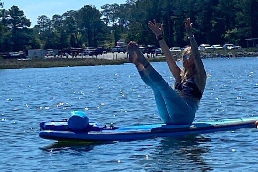 A person lying on a blue board in the water, surrounded by trees and a clear sky. 4