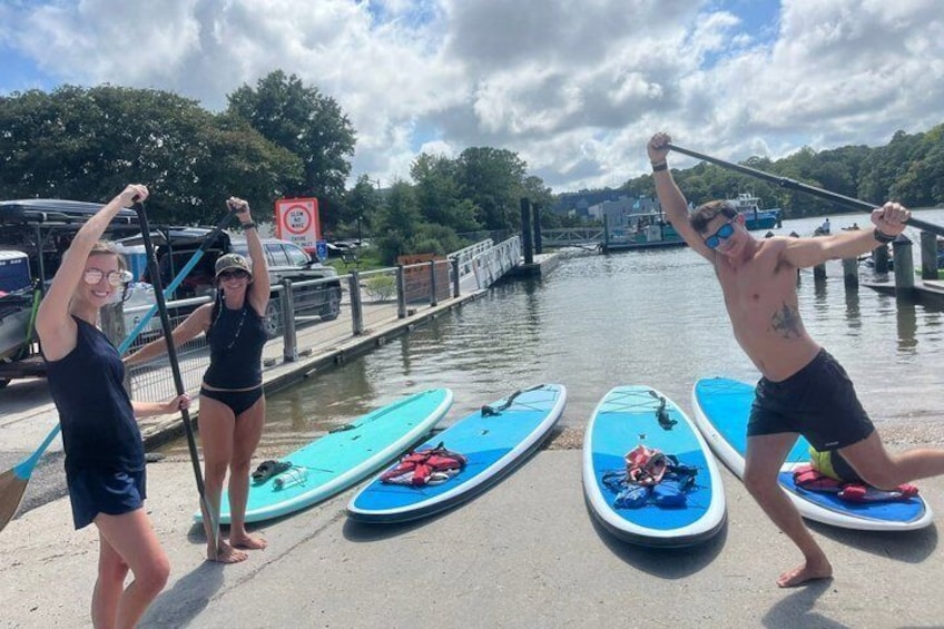 Three paddleboards on a dock, a person standing on the right paddleboard, and another person on the left paddleboard. 3