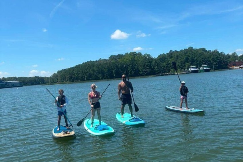 Four people paddleboarding on a calm lake with trees in the background. 5