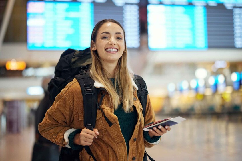 A person with a backpack and a book in an airport terminal. 1