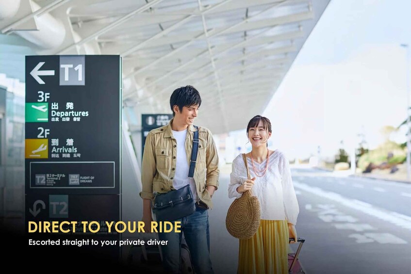 A couple at an airport with a sign indicating departures and arrivals. 5