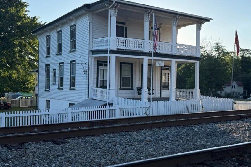 A white two-story building with a balcony, a white picket fence, and a flagpole with an American flag. 5