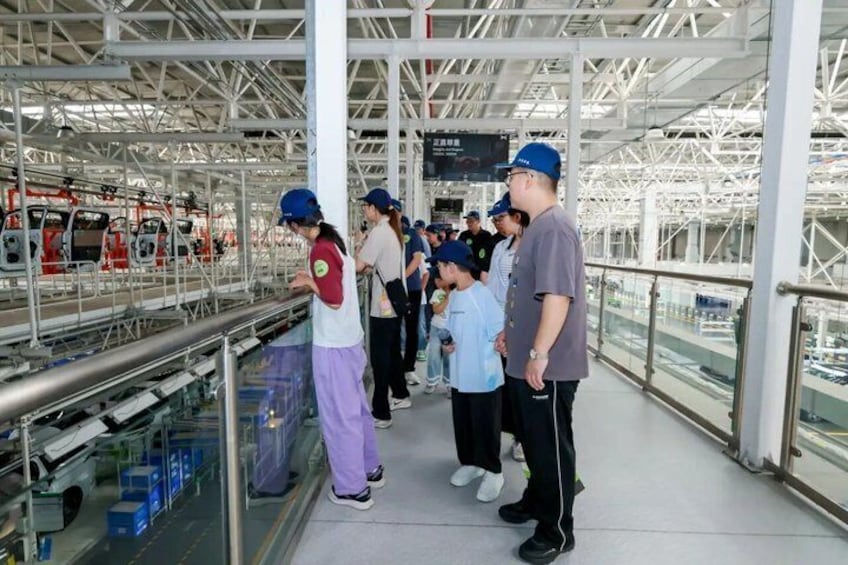 A group of people observing a train in a covered industrial area. 4
