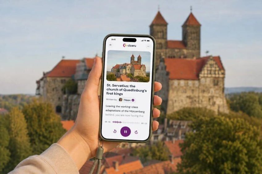 A hand holding a smartphone displaying a castle with a red roof and towers, with trees in the foreground. 1